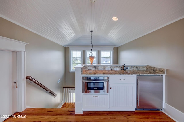 kitchen featuring vaulted ceiling, wood finished floors, wood ceiling, stainless steel appliances, and light stone countertops