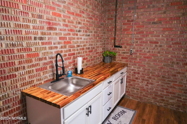 kitchen with hanging light fixtures, white cabinets, butcher block counters, dark hardwood / wood-style flooring, and sink