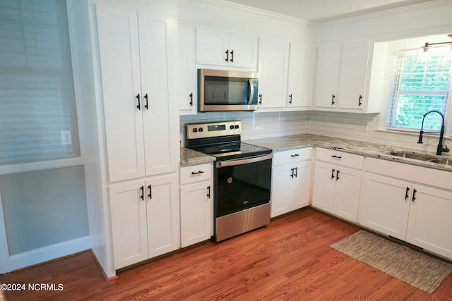 kitchen with stainless steel appliances, white cabinetry, hardwood / wood-style floors, and sink