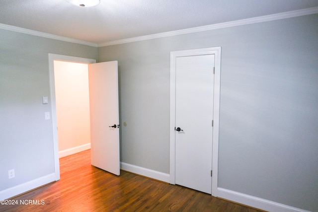 unfurnished bedroom with dark hardwood / wood-style floors and crown molding