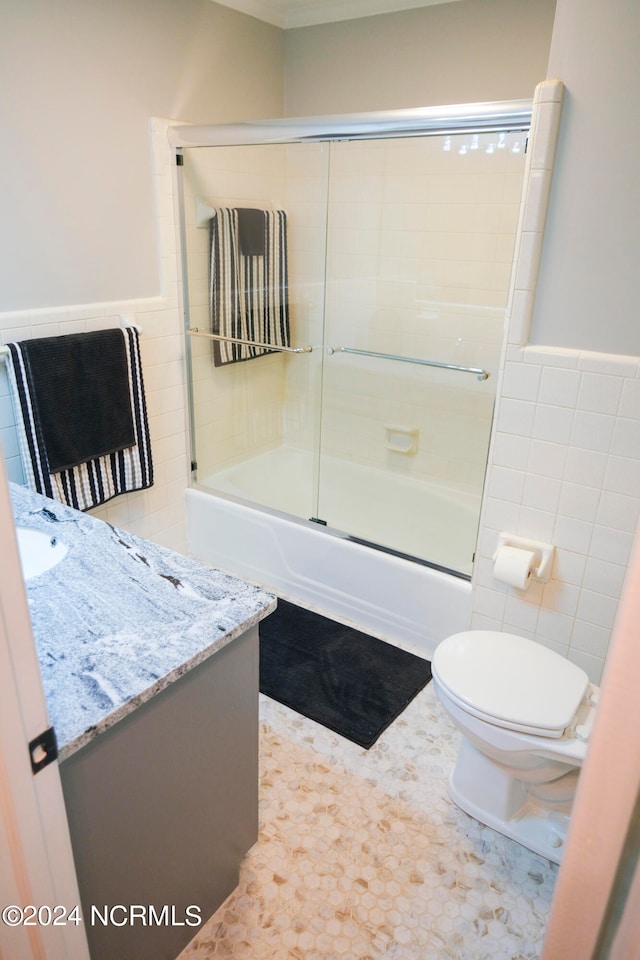 full bathroom with tile walls, tile patterned floors, vanity, enclosed tub / shower combo, and toilet