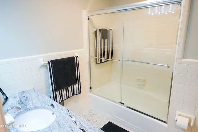 bathroom with enclosed tub / shower combo, tile walls, and sink