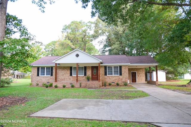 ranch-style house featuring a front yard, a storage shed, and a carport