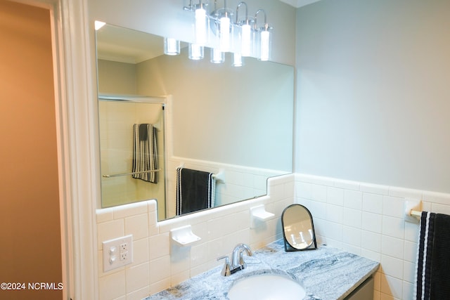 bathroom featuring walk in shower, vanity, and tile walls