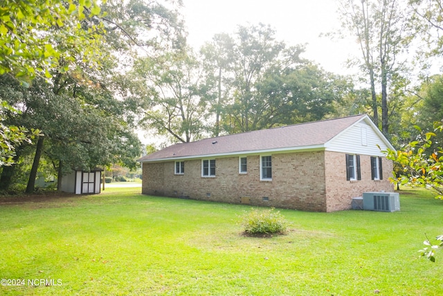 exterior space with central AC unit, a lawn, and a shed