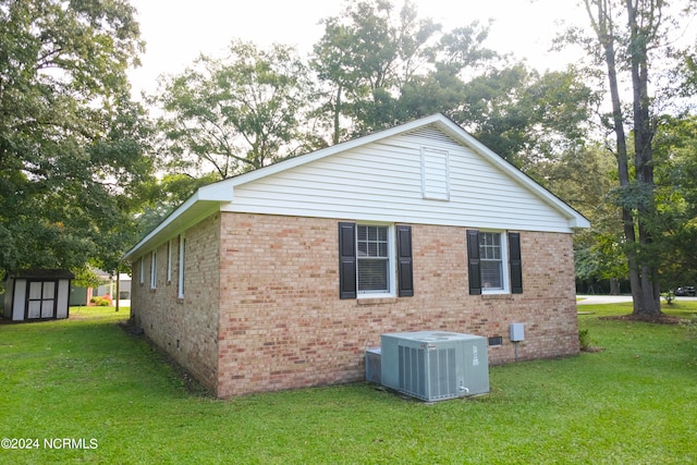 back of house featuring a lawn, a shed, and central air condition unit