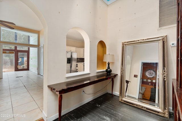 corridor with french doors, light tile patterned flooring, and a towering ceiling