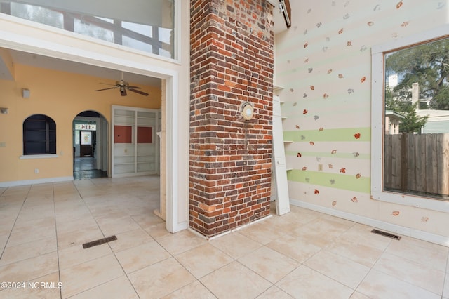 empty room featuring a towering ceiling, ceiling fan, and light tile patterned floors