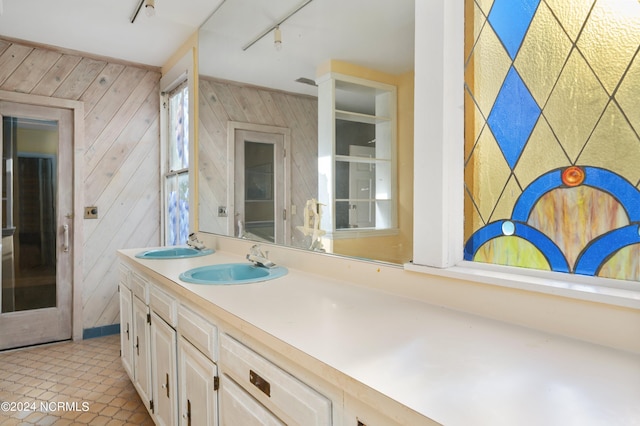 bathroom featuring rail lighting, vanity, wooden walls, and tile patterned floors