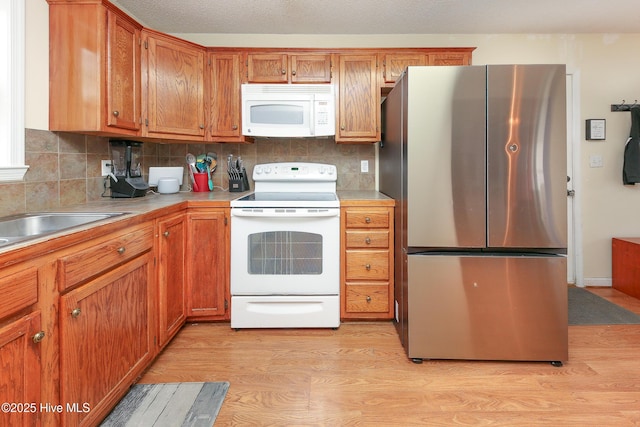 kitchen with backsplash, white appliances, and light wood-type flooring