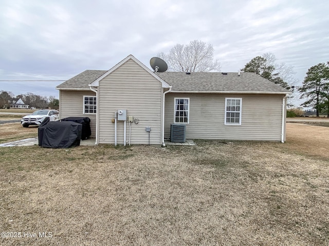 rear view of property featuring cooling unit and a yard