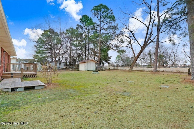 view of yard featuring a wooden deck and a storage shed