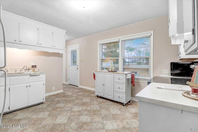 kitchen featuring white cabinetry, sink, and a textured ceiling