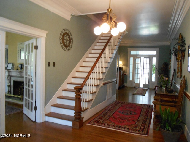 foyer entrance with dark wood-type flooring, a notable chandelier, and ornamental molding