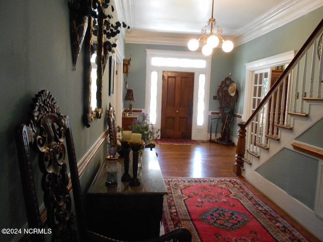 foyer entrance featuring ornamental molding, hardwood / wood-style floors, and a chandelier