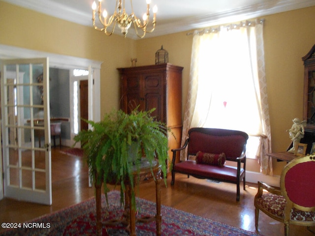 sitting room featuring crown molding, wood-type flooring, and a chandelier