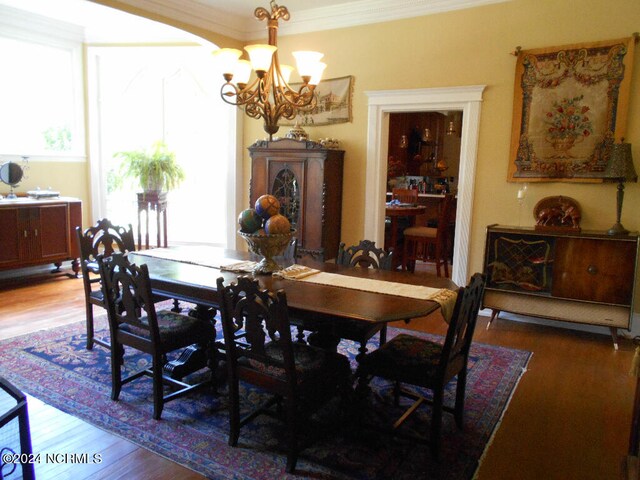 dining room with ornamental molding, an inviting chandelier, and hardwood / wood-style floors