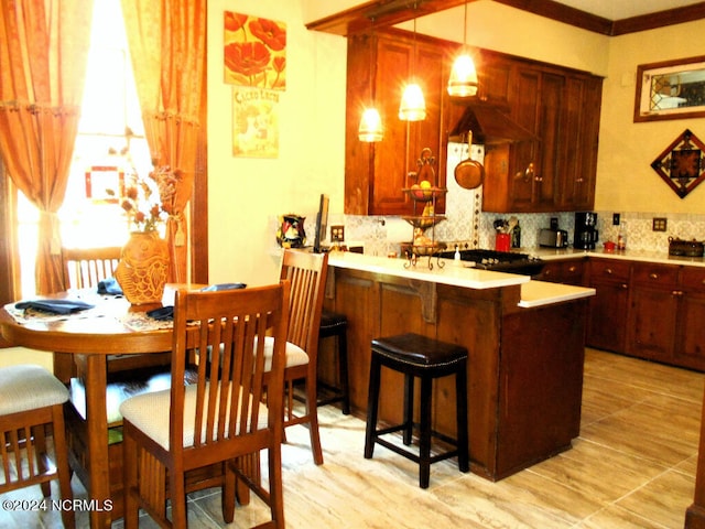 kitchen featuring kitchen peninsula, tasteful backsplash, ornamental molding, custom range hood, and decorative light fixtures