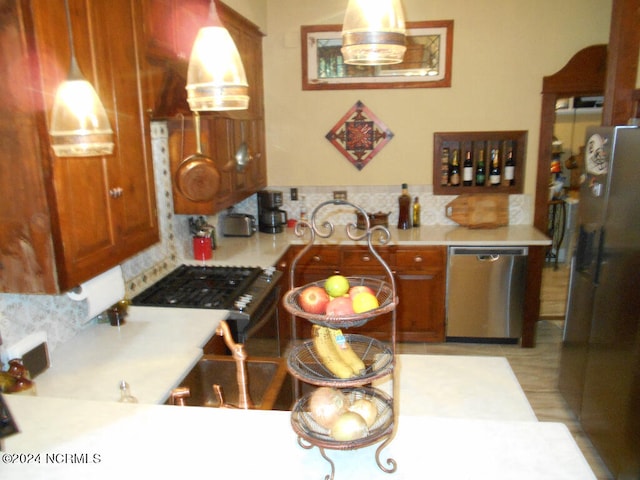 kitchen with appliances with stainless steel finishes, pendant lighting, and decorative backsplash