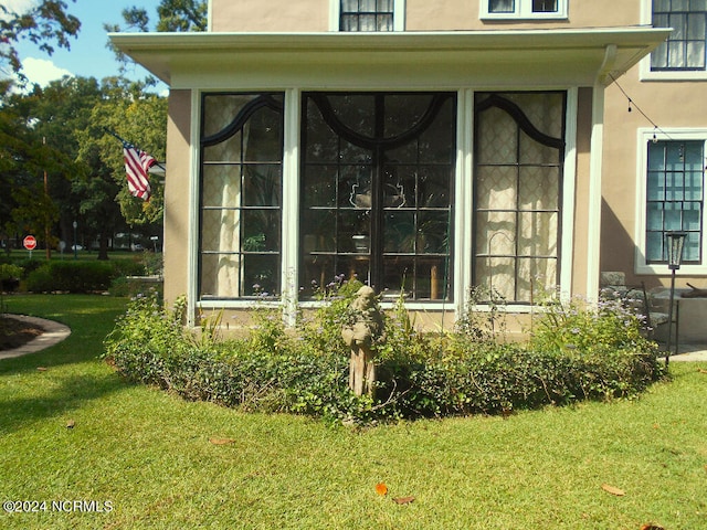 view of property exterior with a sunroom and a lawn