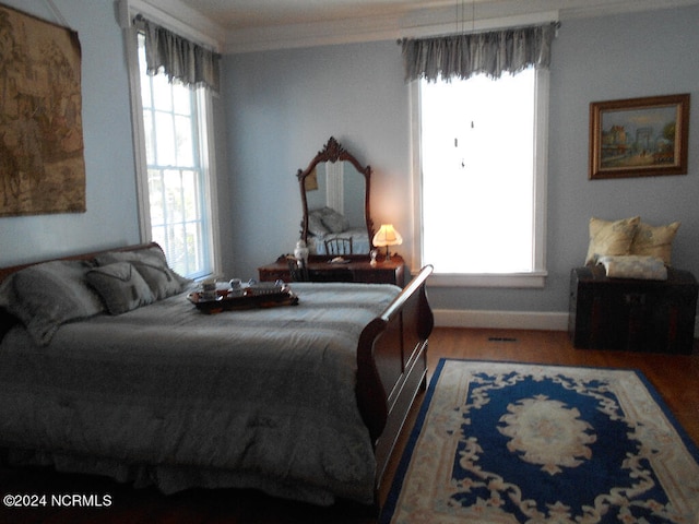 bedroom with ornamental molding, multiple windows, and hardwood / wood-style flooring