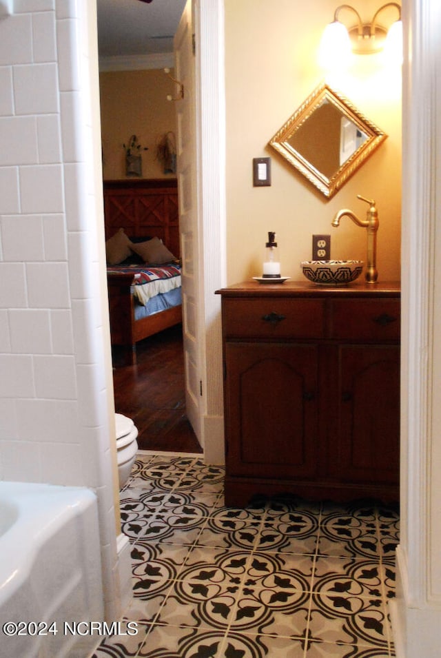 bathroom with ornamental molding, a bathtub, toilet, and tile patterned floors