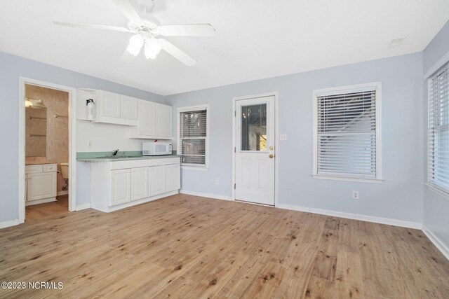 interior space with sink, ceiling fan, and light wood-type flooring