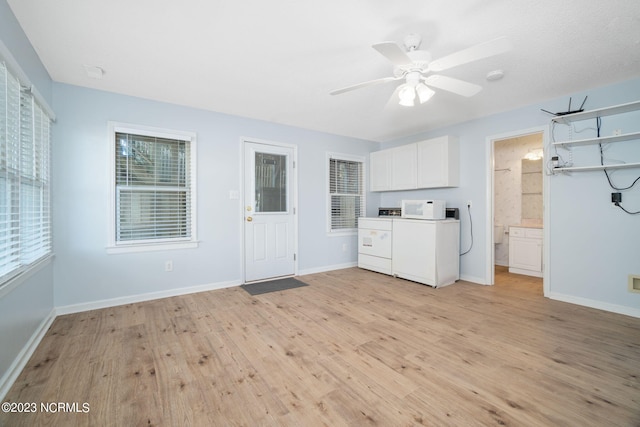 laundry room with cabinets, ceiling fan, a healthy amount of sunlight, washer and clothes dryer, and light hardwood / wood-style flooring