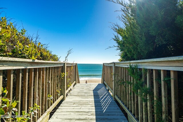 surrounding community featuring a deck with water view and a beach view