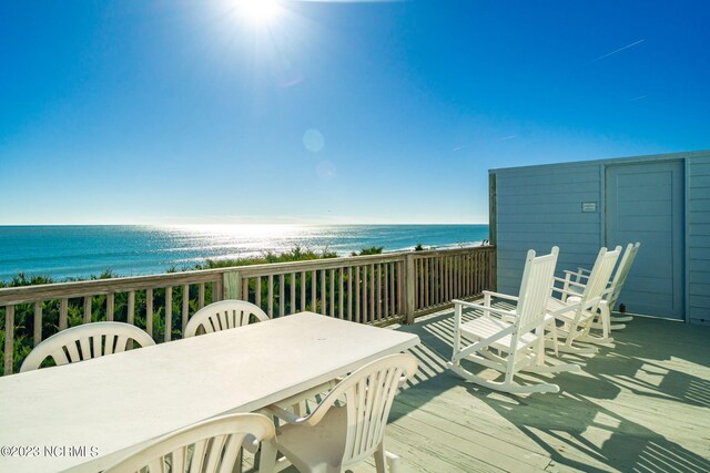 wooden terrace featuring a water view and a view of the beach