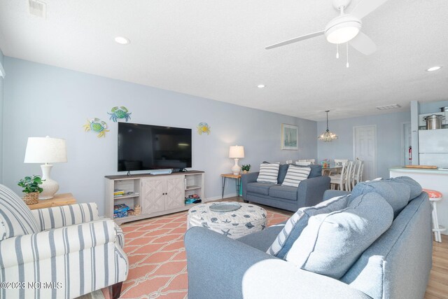 living room with a textured ceiling and ceiling fan with notable chandelier