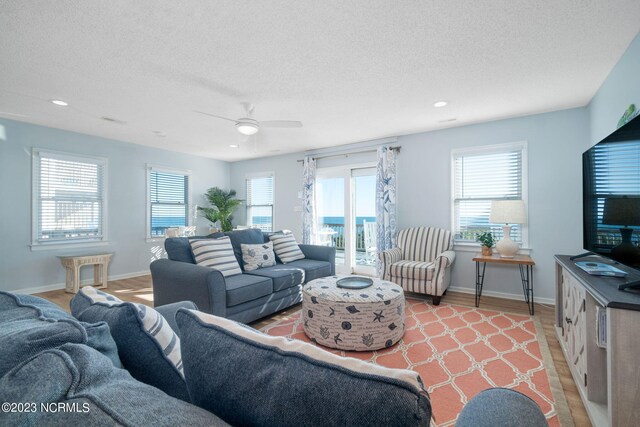 living room with light hardwood / wood-style flooring, ceiling fan, and a wealth of natural light