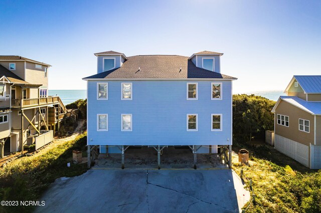 back of property with a water view and a carport