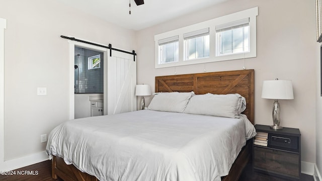 bedroom with dark hardwood / wood-style floors, a barn door, and ceiling fan