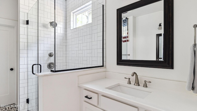 bathroom featuring a shower with door and vanity