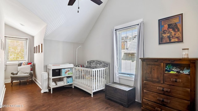 bedroom featuring wood finished floors, baseboards, a crib, a ceiling fan, and vaulted ceiling