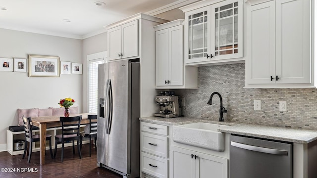 kitchen featuring backsplash, appliances with stainless steel finishes, a sink, and dark wood finished floors