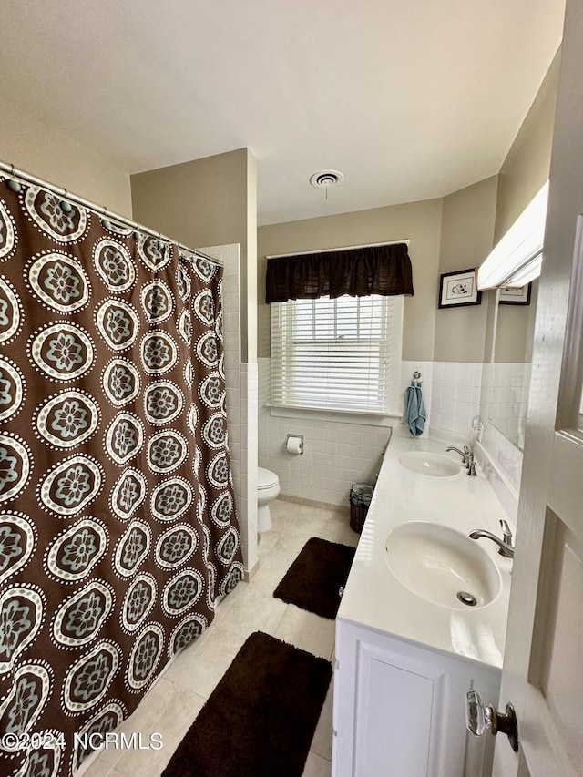 207 W Eden St, Edenton, NC 27932 - bathroom with tile walls, tile patterned floors, toilet, double vanity, and wainscoting