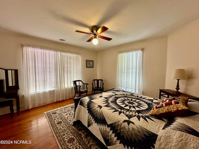 bedroom featuring multiple windows, ornamental molding, ceiling fan, and hardwood / wood-style flooring