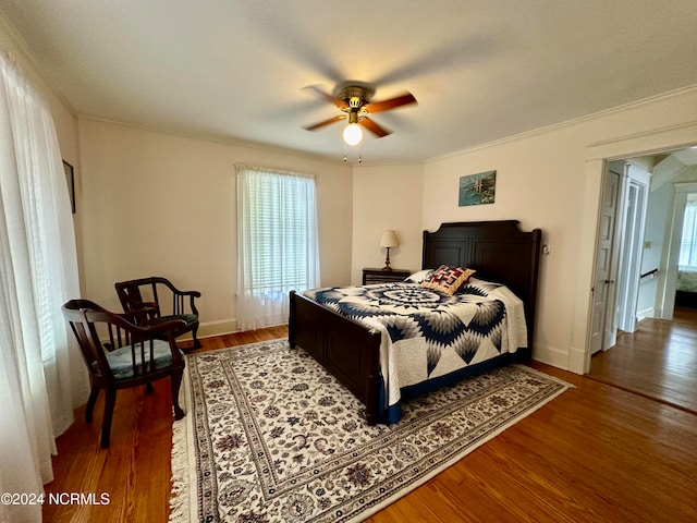 bedroom with ceiling fan, ornamental molding, and dark wood-type flooring