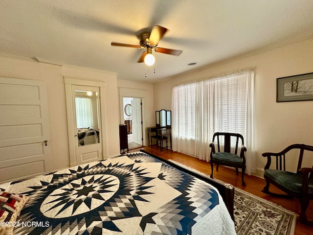 bedroom with ceiling fan, hardwood / wood-style flooring, crown molding, and a textured ceiling