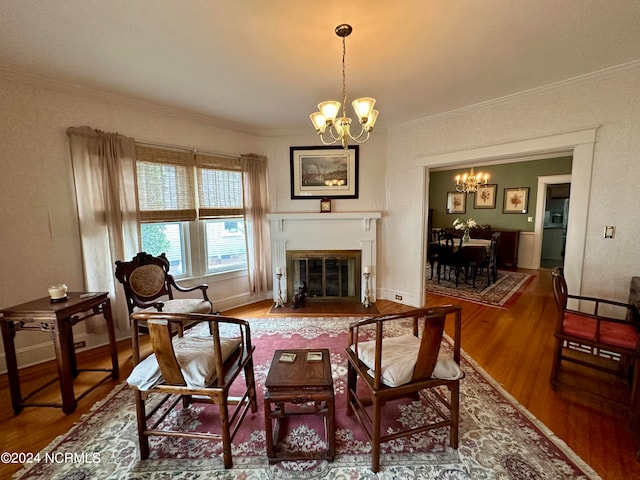 living area with ornamental molding, hardwood / wood-style floors, and a notable chandelier