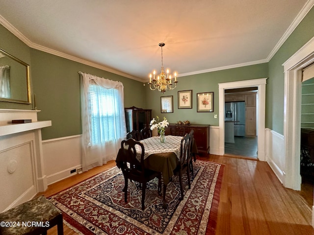 dining area featuring wood-type flooring, crown molding, and a chandelier