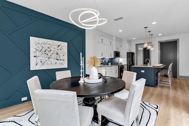 dining space featuring an inviting chandelier, light hardwood / wood-style floors, and sink