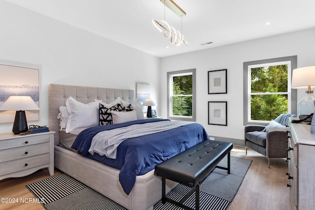 bedroom featuring wood-type flooring, a notable chandelier, and multiple windows