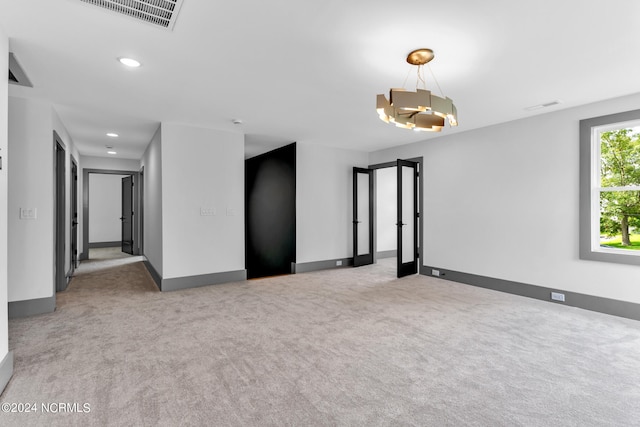 spare room with a chandelier and light carpet