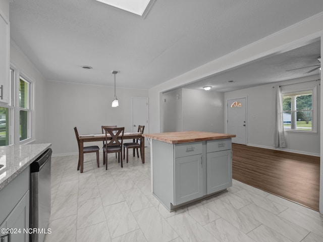 kitchen featuring light wood-type flooring, gray cabinetry, decorative light fixtures, butcher block countertops, and stainless steel dishwasher