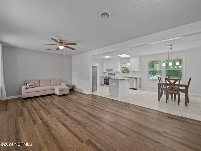 living room featuring ceiling fan, a textured ceiling, light hardwood / wood-style flooring, and sink