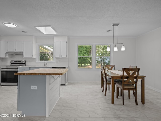 kitchen with sink, white cabinetry, a kitchen island, stainless steel appliances, and decorative light fixtures