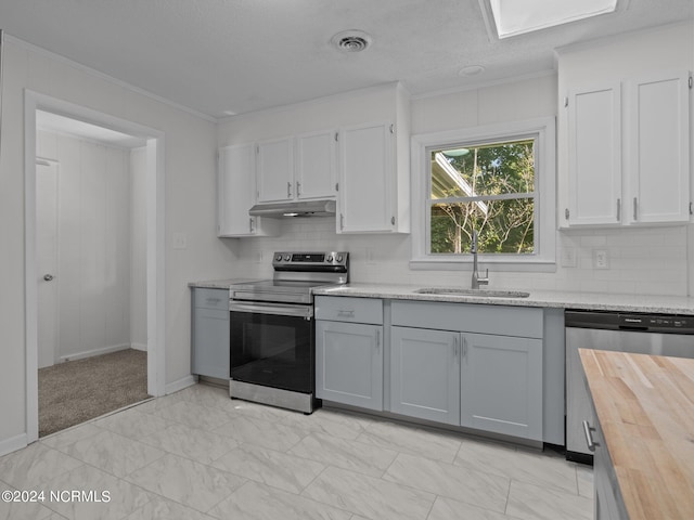 kitchen with appliances with stainless steel finishes, tasteful backsplash, ornamental molding, wood counters, and sink